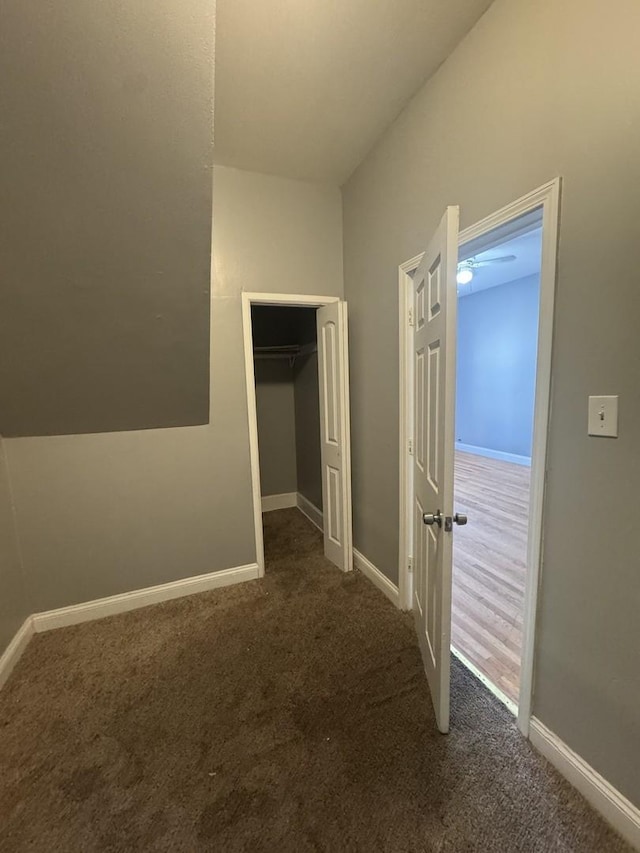 unfurnished bedroom featuring baseboards, dark carpet, and a closet