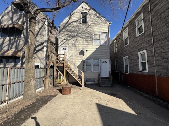 rear view of house with entry steps and fence
