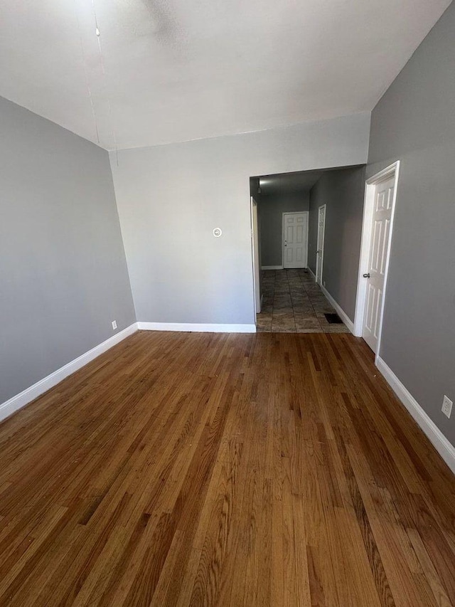 unfurnished room with baseboards and wood finished floors