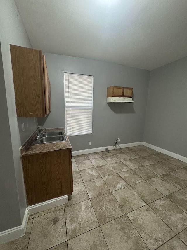 washroom featuring baseboards, a sink, and light tile patterned flooring