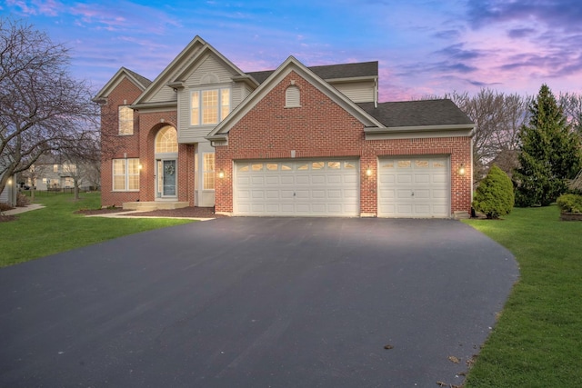 traditional home featuring driveway, brick siding, a yard, and a garage
