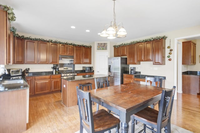 kitchen featuring a center island, light wood-style floors, an inviting chandelier, appliances with stainless steel finishes, and under cabinet range hood