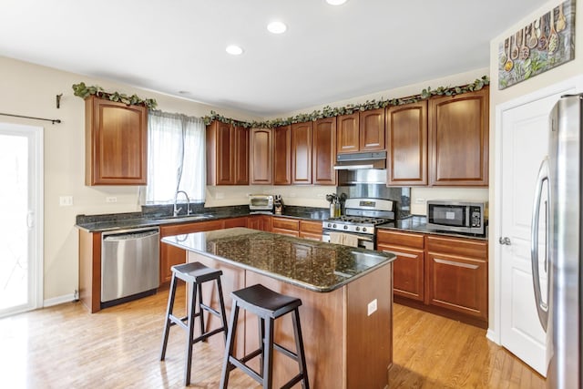 kitchen with stainless steel appliances, a center island, recessed lighting, a kitchen bar, and under cabinet range hood