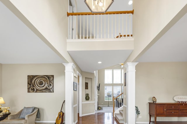entrance foyer with wood finished floors, decorative columns, baseboards, and stairs