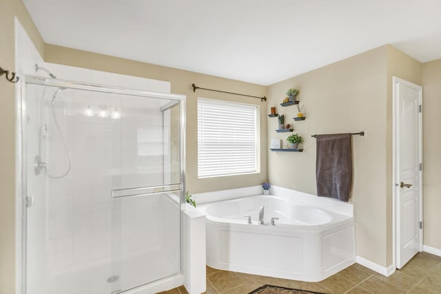 bathroom featuring baseboards, a bath, tile patterned floors, and a stall shower