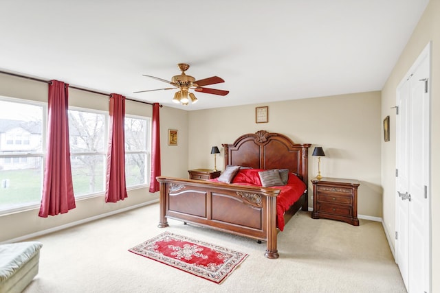 bedroom with ceiling fan, baseboards, a closet, and light colored carpet