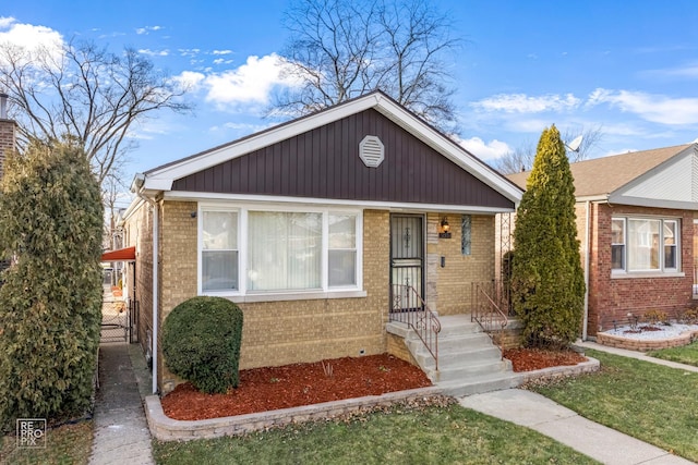 bungalow-style home featuring brick siding, a front yard, and a gate