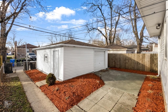 detached garage featuring fence and driveway