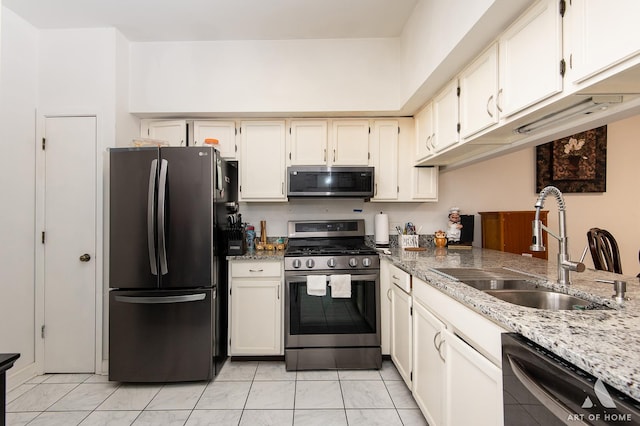 kitchen with stainless steel appliances, a sink, stone counters, and white cabinets
