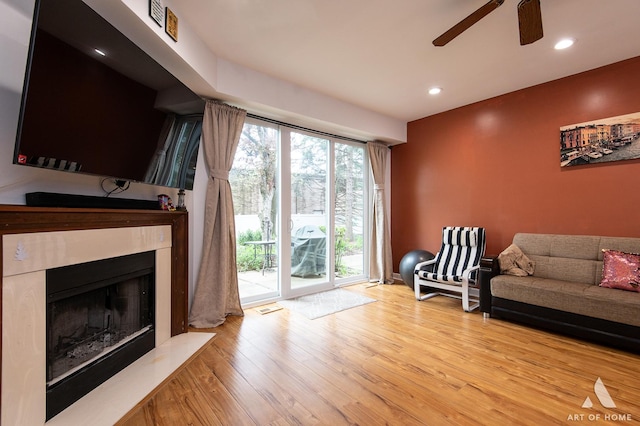 living room featuring a ceiling fan, wood finished floors, a fireplace with flush hearth, and recessed lighting
