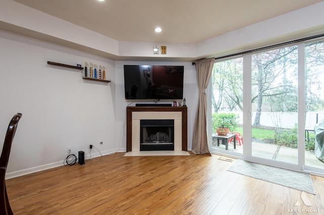 unfurnished living room featuring wood finished floors, a fireplace with flush hearth, baseboards, and recessed lighting