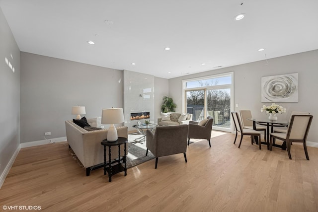 living area featuring light wood-type flooring, baseboards, a fireplace, and recessed lighting