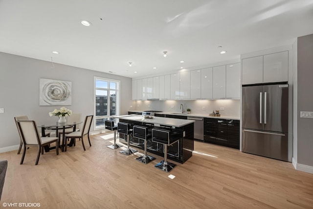 kitchen featuring a sink, white cabinetry, stainless steel appliances, and light wood-style floors