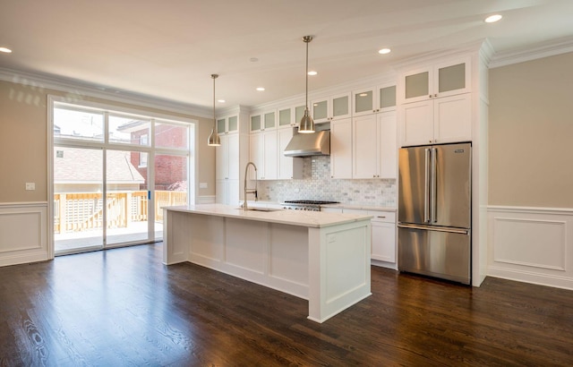 kitchen with a decorative wall, crown molding, a sink, exhaust hood, and appliances with stainless steel finishes