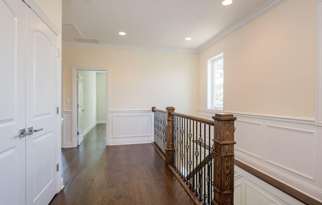 hallway with a decorative wall, an upstairs landing, a wainscoted wall, ornamental molding, and dark wood-style floors