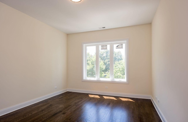 spare room with baseboards, visible vents, and dark wood finished floors
