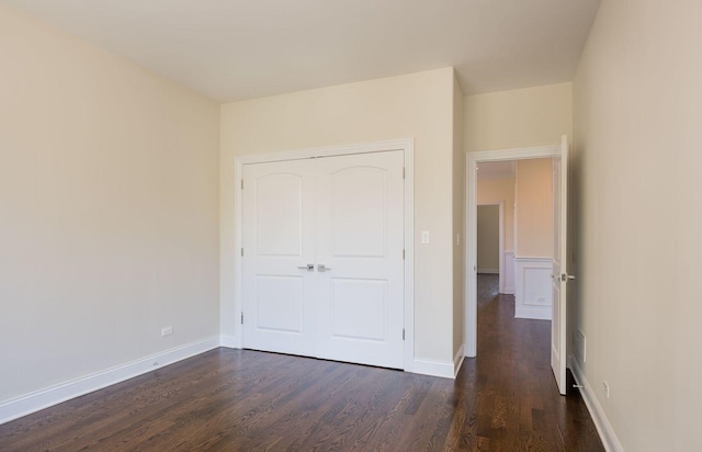 unfurnished bedroom featuring baseboards and dark wood-style flooring