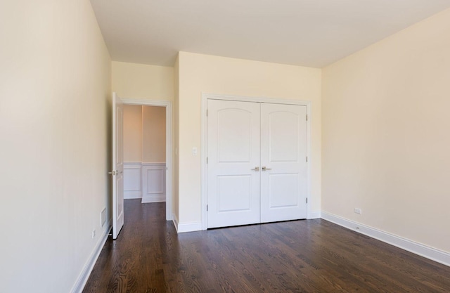 unfurnished bedroom with visible vents, baseboards, a closet, and dark wood finished floors
