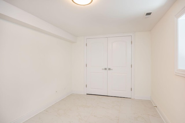 unfurnished bedroom with a closet, visible vents, marble finish floor, and baseboards