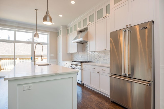 kitchen featuring white cabinets, under cabinet range hood, a sink, crown molding, and high quality appliances