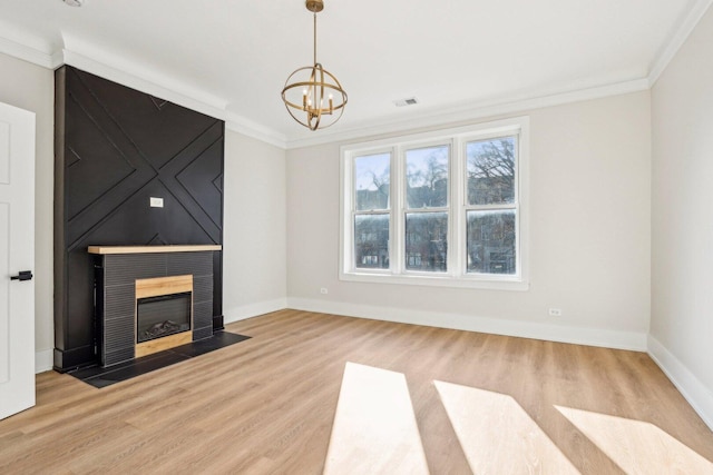 unfurnished living room featuring a notable chandelier, crown molding, and wood finished floors