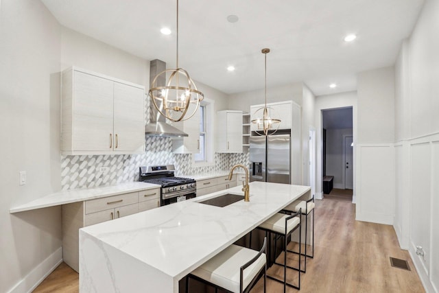 kitchen featuring stainless steel appliances, a sink, light wood-style flooring, tasteful backsplash, and a notable chandelier