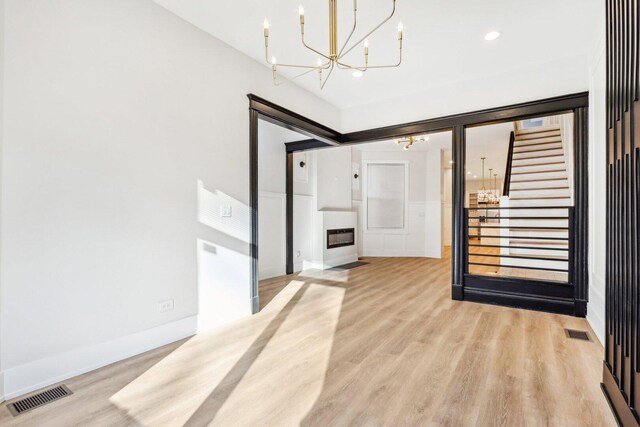 entrance foyer featuring stairway, visible vents, light wood finished floors, and an inviting chandelier