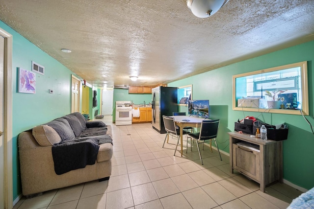 living area featuring baseboards, visible vents, a textured ceiling, and light tile patterned floors