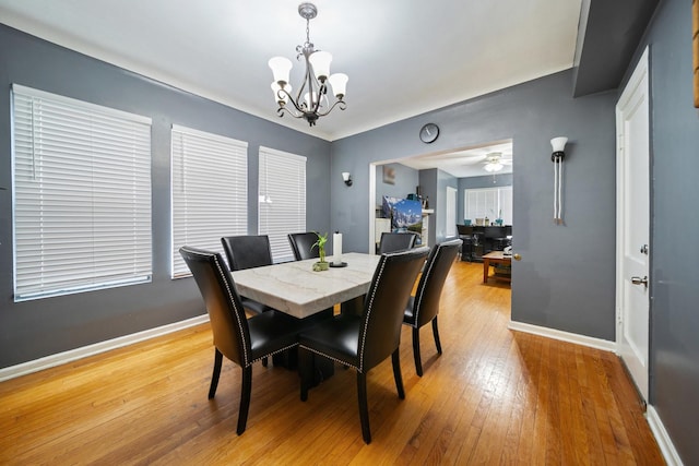 dining space featuring light wood finished floors, baseboards, and ceiling fan with notable chandelier