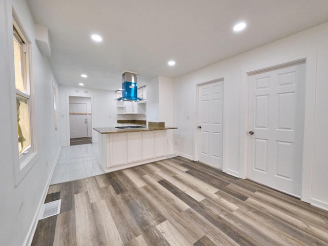 14923 Wood St, Harvey, IL 60426 - kitchen with a peninsula, light wood-type flooring, island range hood, and baseboards