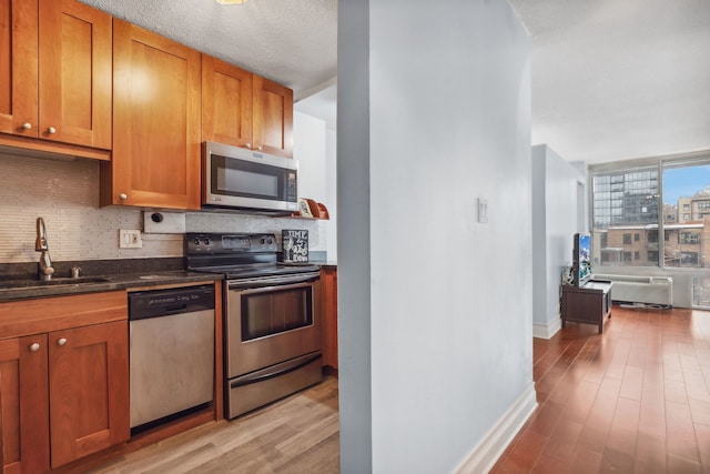kitchen with light wood-type flooring, a sink, backsplash, and stainless steel appliances