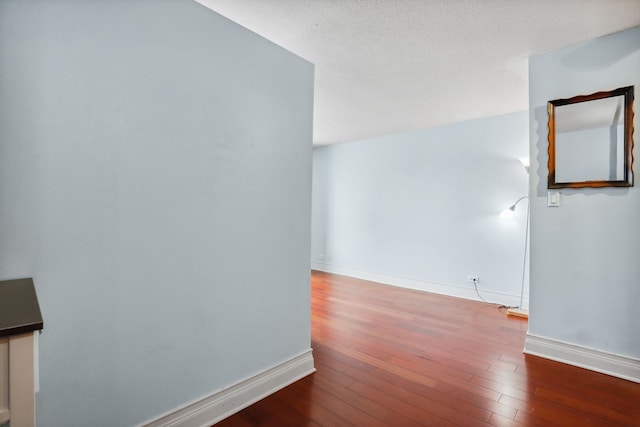spare room featuring baseboards and hardwood / wood-style flooring