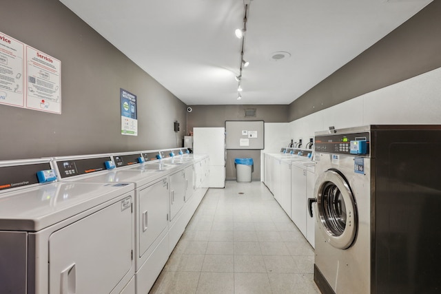 community laundry room with rail lighting and independent washer and dryer