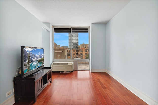 living area featuring a textured ceiling, baseboards, a wall of windows, and wood finished floors
