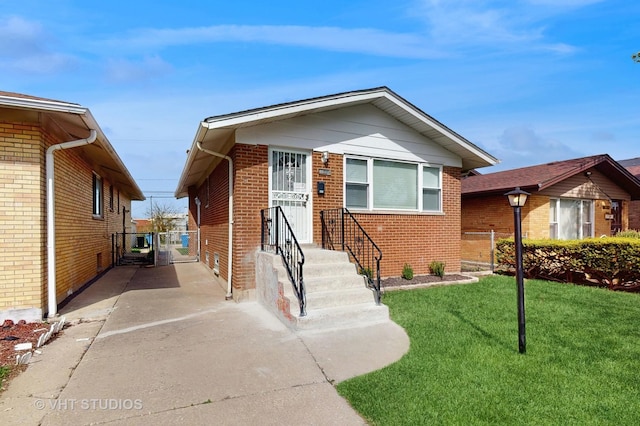 view of front of home with brick siding, a gate, a front lawn, and driveway