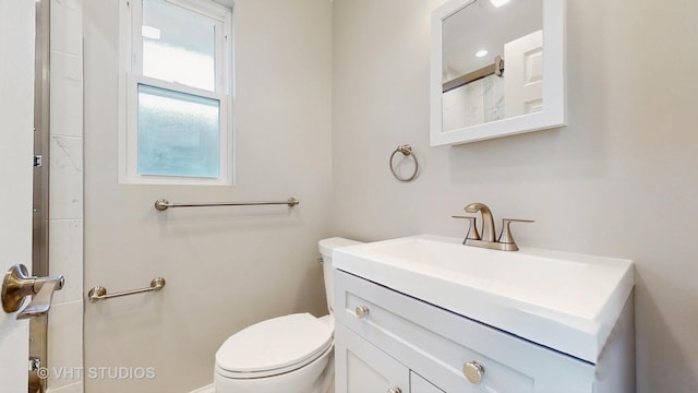 bathroom featuring vanity, walk in shower, and toilet