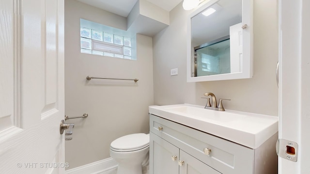 bathroom featuring vanity, baseboards, a shower with door, and toilet