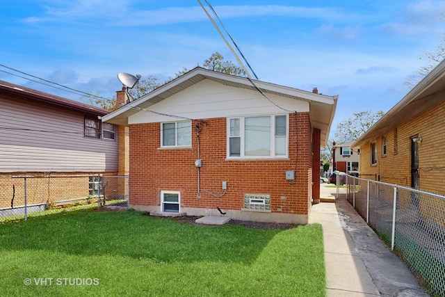 back of property with a yard, brick siding, a chimney, and a fenced backyard