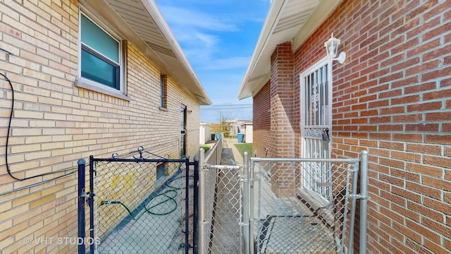 view of side of property featuring fence, a gate, and brick siding
