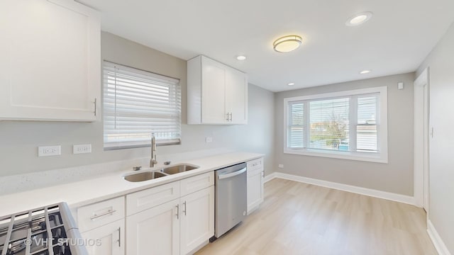 kitchen with light countertops, white cabinets, a sink, and dishwasher
