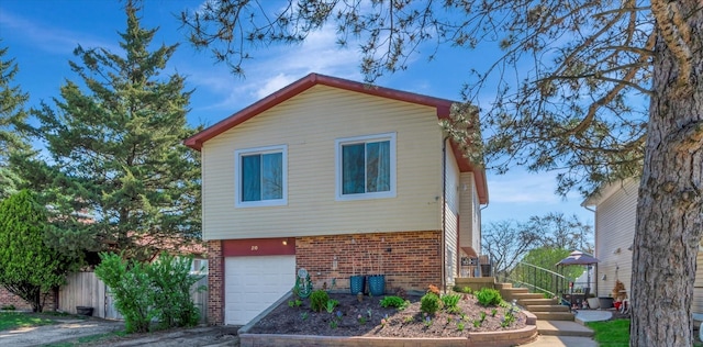 view of property exterior featuring fence, an attached garage, driveway, and brick siding