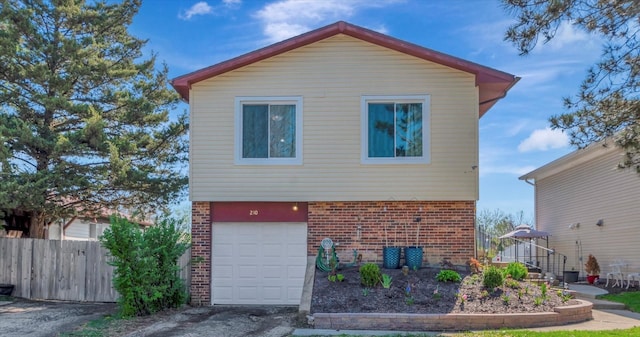 exterior space with brick siding, a garage, fence, and driveway