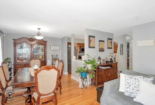 dining space with baseboards and light wood-type flooring