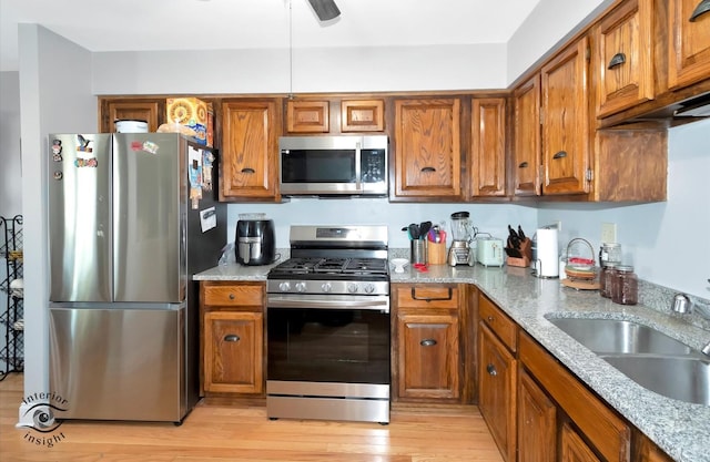 kitchen with brown cabinetry, a sink, and appliances with stainless steel finishes