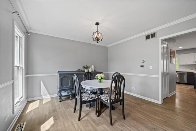 dining room featuring visible vents, ornamental molding, wood finished floors, baseboards, and a chandelier
