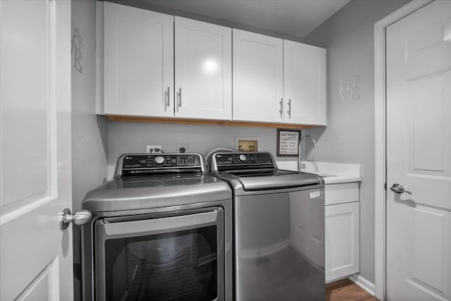 laundry area with wood finished floors, a sink, cabinet space, and washing machine and dryer