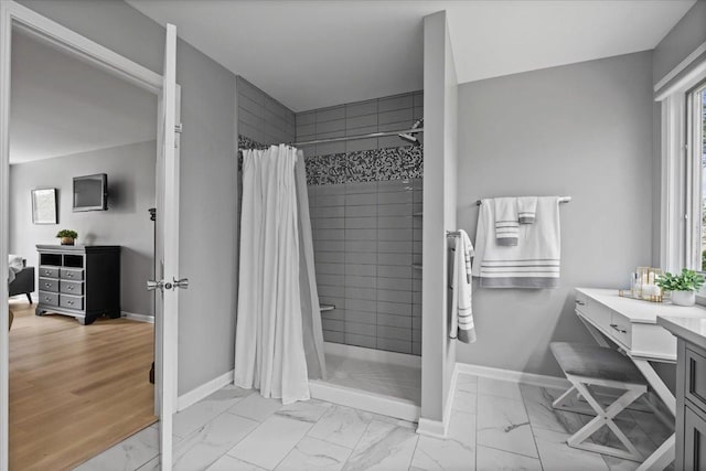 full bathroom featuring baseboards, marble finish floor, a stall shower, and vanity