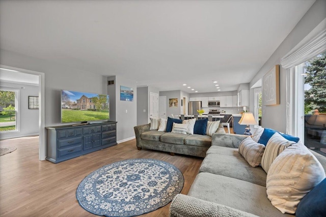 living area featuring baseboards, plenty of natural light, recessed lighting, and light wood-style flooring