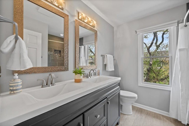 full bathroom with double vanity, toilet, baseboards, a sink, and a tile shower