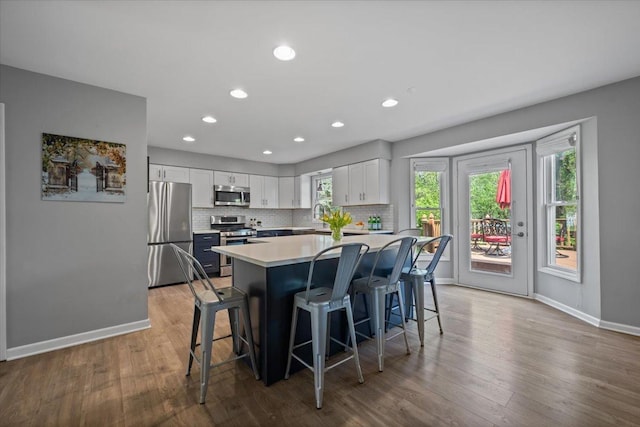 kitchen featuring a kitchen breakfast bar, light countertops, baseboards, white cabinets, and stainless steel appliances